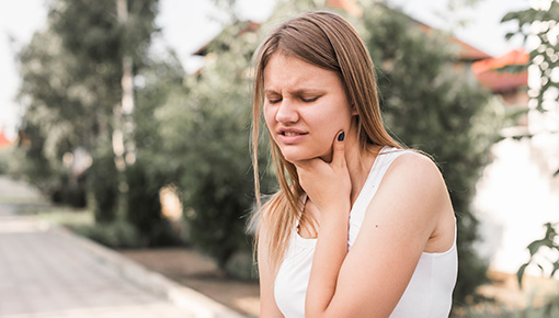 Woman with swallowing disorder holding her jaw.