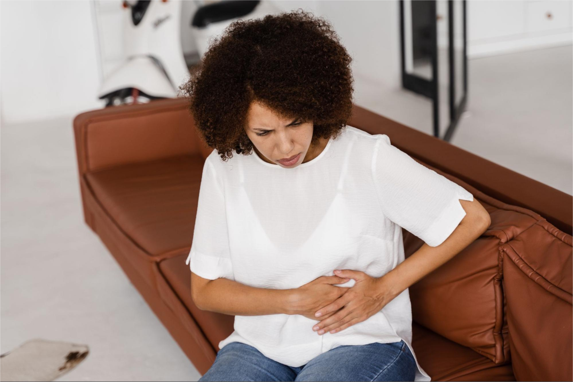 Woman holding stomach on sofa.